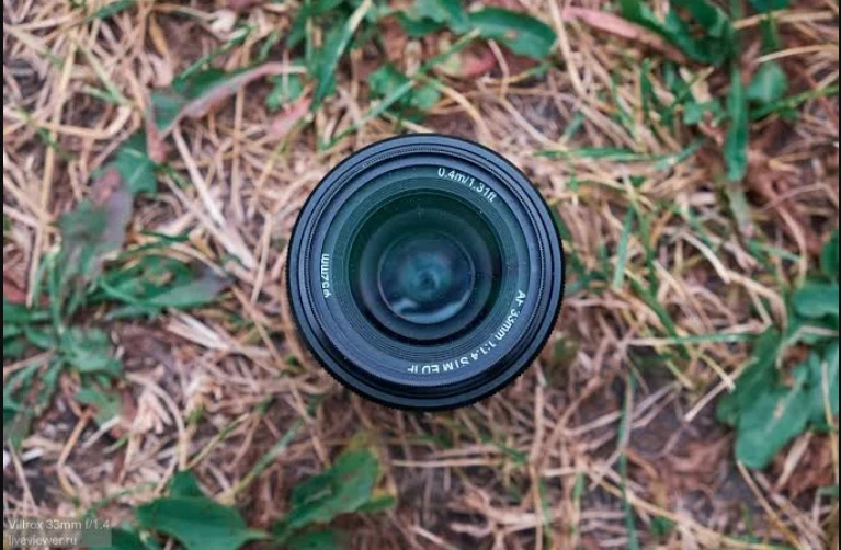 Вид згори на передню лінзу об'єктива Viltrox 33mm f/1.4 з маркуванням діаметра 52 мм, мінімальної дистанції 0.4 м та оптичного скла низької дисперсії ED